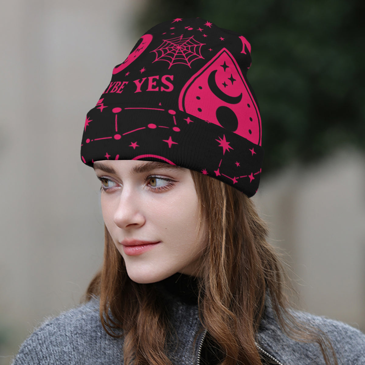 Person wearing a black beanie with pink Ouija Board designs and text