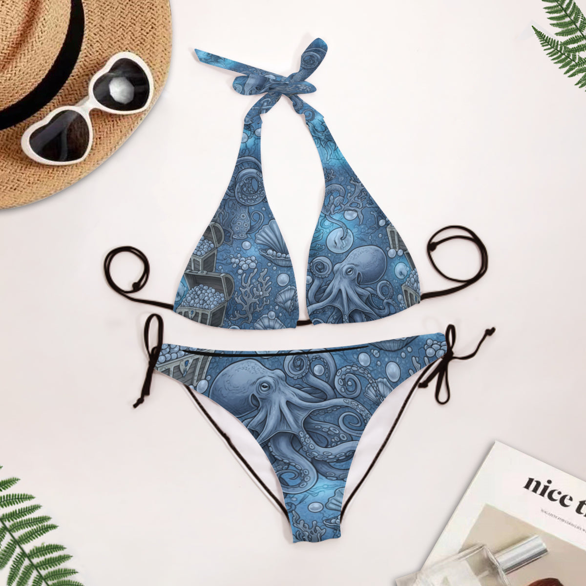 Blue under the sea patterned bikini set with sunglasses, hat, and magazine on a light background