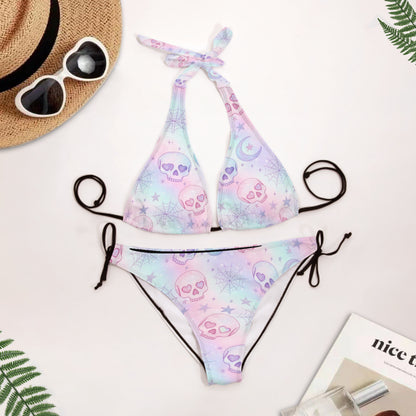 Pastel skull pattern bikini set with sunglasses and a hat on a light background